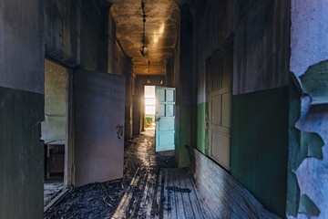 Obraz premium Sinister and creepy Corridor of abandoned hospital after fire. Ceiling in black soot