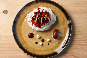Fresh Pavlova fruit cake and berry ice cream dessert on wooden table background, close-up