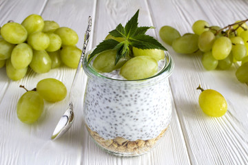 Pudding with chia, muesli and grapes on the white wooden background