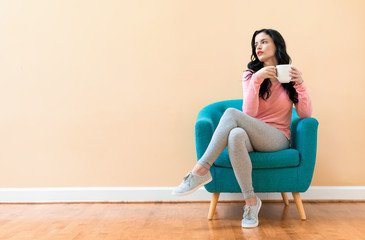 Young woman drinking coffee in a chair
