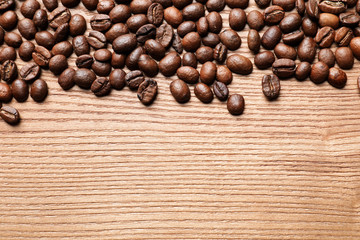 Roasted coffee beans on wooden background with space for text, top view