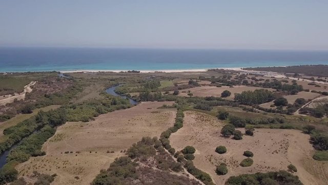 Drone flight at Berchida beach, Sardinia, Italy. Aerial view of mediterranean coast, with sandy beach and green vegetation. Concept of travel, tourism, holiday, vacation, trip, exploration, nature.