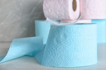 Roll of toilet paper with feather on grey table. Space for text