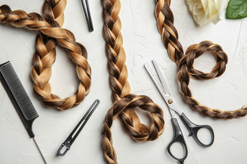 Flat lay composition with braids and hairdresser's tools on light background