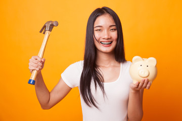Asian woman with pig coin bank and hammer.