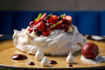 Homemade Pavlova fruit cake and berry ice cream dessert on wooden table background, close-up