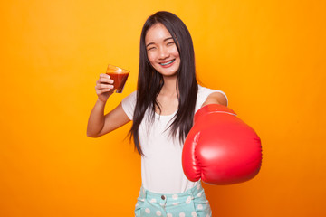 Young Asian woman with tomato juice and boxing glove.