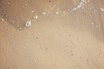 Fototapeta na wymiar Background of sea sand with seashells on the beach of the sea, ocean with waves