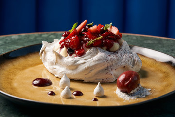 Homemade Pavlova fruit cake and berry ice cream dessert on wooden table background, close-up