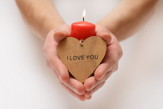 Red candle in hands. Inscription on the heart, I love you - Powered by Adobe
