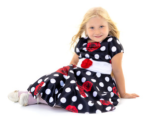 Little girl is sitting on the floor.