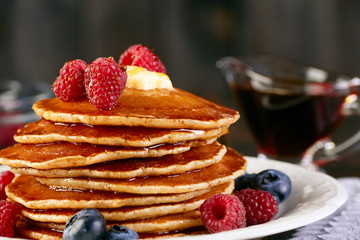 Stack of pancakes with berries and maple syrup