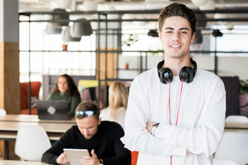 Waist up portrait of contemporary young man with headphones cheerfully looking at camera while...