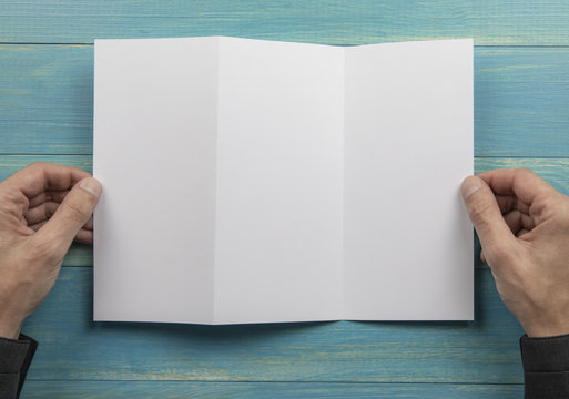 Mens hands holding white booklet