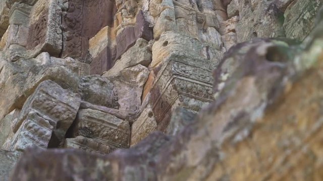 Pan up to a female sculpture (devata) on an ancient Khmer temple.