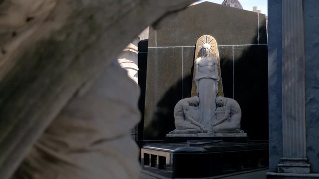 Two men praying to Jesus statue in La Recoleta Cementery focus rack