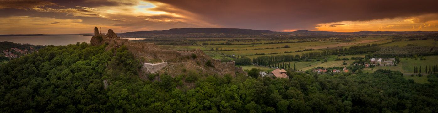Aerial sunset panorama of ruined medieval Szigliget castle in Hungary above the Lake Balaton with orange yellow sky