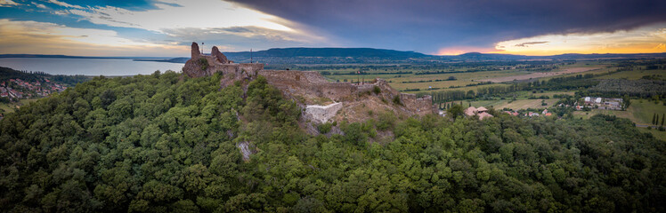 Aerial sunset panorama of ruined medieval Szigliget castle in Hungary above the Lake Balaton with orange yellow sky