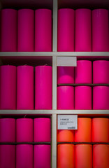 Purple, pink, orange small and large candles stacked on a shelf