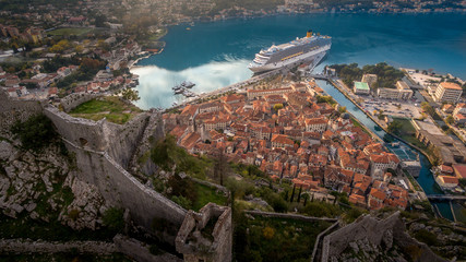 Aerial view of medieval Kotor with red roofs, cruise ship on the bay in Montenegro