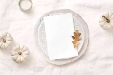 bright elegant menu or invitation card mockup with festive autumn / fall themed table setting with white pumpkins, candle and natural leaf, ideal for  thanksgiving or seasonal weddings - flat lay