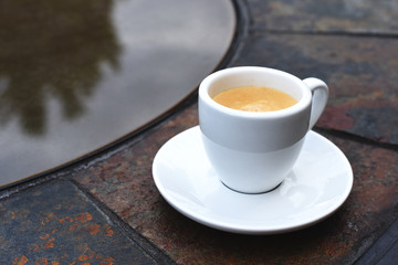 Classic espresso drink with saucer on a glass and stone table