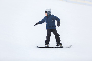 cute young boy, brave kid in gray helmet and orange googles, in blue jacket snowboarding on white snow mountain. winter sport, active lifestyle concept