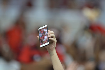Mobile in the hand of spectators.