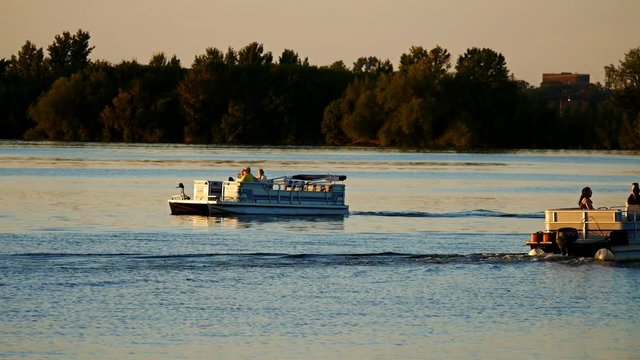 Silhouette of people enjoying boating on a calm lake in Bemidji, Minnesota at sunset. Two Pontoon boats.