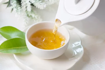 Foto op Plexiglas Thee Sluit het gieten van hete zwarte thee in een witte theekop, theeceremonietijdconcept