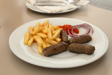 Cevapcici or cevapi, rolls meat, onion, fries and ajvar