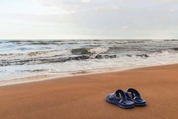 Fototapeta na wymiar Slippers on the sand near the sea
