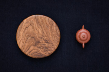 Handmade black walnut round wooden pallet and teapot on dark blue hand-dyed burlap