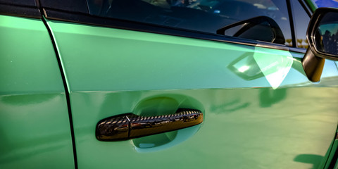 Green car with bronze handle and side mirror