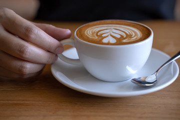 women  Holding coffee cup, wooden table  cafe while having coffee