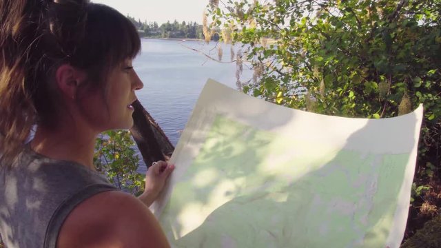Handheld footage over the shoulder of a cute hipster girl reading and looking at a map of the park she is in
