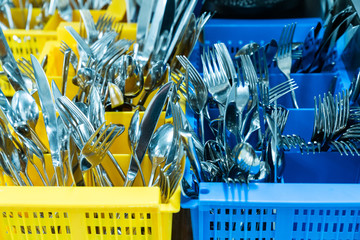 silverware and cutlery in colorful palstic ocntainer in an industrial restaurant kitchen clean and fresh out of the dishwasher © makasana photo