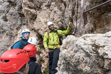 Gardinen A male mountain guide instructs young climbers at the start of a steep Via Ferrata in the Dolomites of northern Italy in Alta Badia © makasana photo