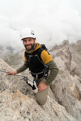 Obraz premium young handsome male university student on a steep and exposed rock face climbs a Via Ferrata in Alta Badia in the South Tyrol