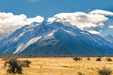 MOUNTAIN TOP COVERED WITH SNOW AND CLOUD.  Expansive Landscape of mountain covered with snow and large passing cloud at Mount Cook, New Zealand.