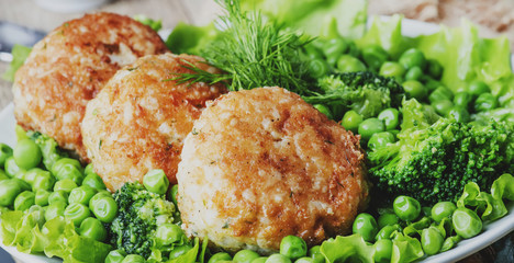 Fish cutlets or meatballs from cod and pike perch with a garnish of green peas and broccoli, rustic...