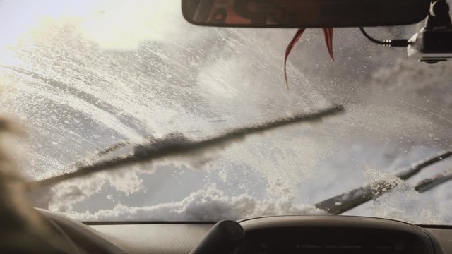 Automobile's windscreen wipers are cleaning the snow. Footage from the car.