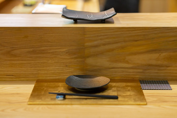 empty black ceramic dish on wooden bar, Omakase style Japanese.