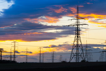 Fototapeta premium Electricity - Power energy Industry - Electric poles at the sunset with coloful sky