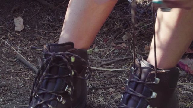 Cute hipster girl tying her hiking boots up at the park