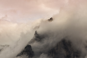 Dramatic sunset with rain clouds and rocky peaks in the Dolomite Alps, Italy, in summer