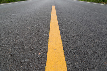 The yellow line on the road with tree and sky
