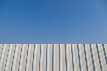 White corrugated metal fence with blue sky