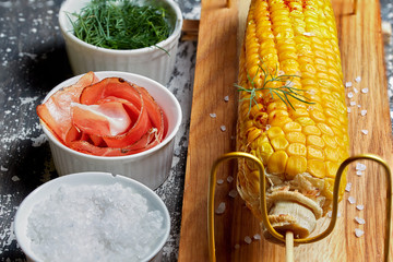 Grilled corn cob with bacon, salt and herbs.  Concept of feed corn in the restaurant