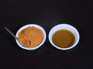 Turmeric And Mustard Oil on Wooden Background,Mustard Oil and Turmeric in White Bowl on Wooden Background, Haldi and Sarso ka tel, Haldi and sarso ka tel in White Bowl on Wooden Background,